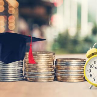 black graduation cap on stacks of coins, white clock on a table
