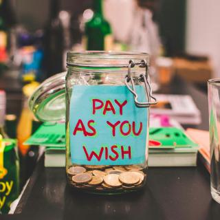 clear, coin-filled glass mason jar with pay as you wish sticker