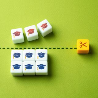 block with scissors icon cuts through blocks of red and blue graduation caps