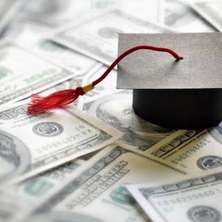mortarboard on top of hundred dollar bills